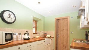 Una cucina con forno a microonde, bollitore e pensili in legno.
