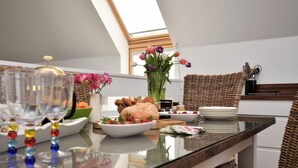 A modern kitchen with a skylight, a dining table set with plates, glasses, and a vase of flowers. - 3 Bed in Bideford (oc-40820) (Northam)