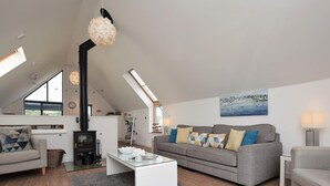 A modern loft-style living room with a fireplace, a sofa set, a coffee table, and a painting on the wall. - 3 Bed in Bideford (oc-40820) (Northam)