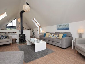 A modern loft-style living room with a fireplace, a sofa set, a coffee table, and a painting on the wall. - 3 Bed in Bideford (oc-40820) (Northam)