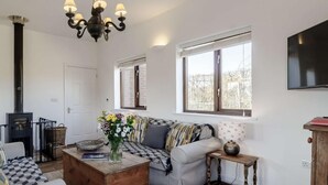 Ein gemütliches Wohnzimmer mit einer Couch, einem Holztisch, einem Kamin und einem an der Wand befestigten Fernseher.