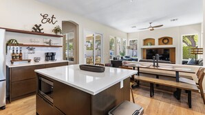 Una cocina moderna con una isla central, electrodomésticos integrados y un comedor con banco y mesa.