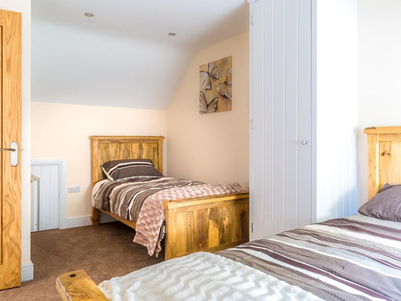 A bedroom with a wooden bed, a wooden wardrobe, and a white door.