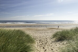 A sandy beach with dunes and a person walking. - 2 Bed in Morpeth (oc-36925) (Widdrington)