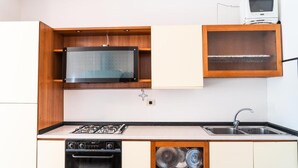 Una cocina compacta con microondas, horno y un lavamanos pequeño.