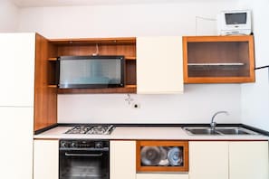 A compact kitchen with a built-in microwave, oven, and a small sink. - Beautiful and Well-equipped Flat for Four (San Michele al Tagliamento)