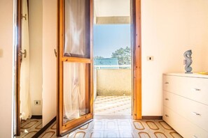 An open door leading to a balcony with a view of a building and trees. - Beautiful and Well-equipped Flat for Four (San Michele al Tagliamento)