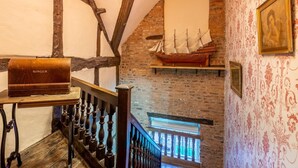 Una habitación con vigas de madera a la vista, un modelo de barco, una máquina de coser Singer y una araña.