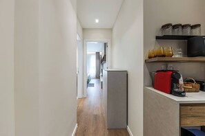 A narrow hallway with a refrigerator, a coffee machine, and jars on a shelf. - Kiti Studio | Beach Escape by PikHost (Vlorë)