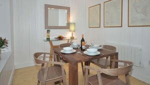 Una zona pranzo con tavolo in legno, sedie, uno specchio e quadri appesi al muro.