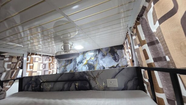 Une chambre d’hôtel avec un lit, un ventilateur de plafond, un mur à motifs et une fenêtre.