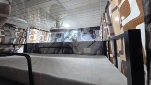 Une chambre avec un lit, un ventilateur de plafond et des murs à motifs.
