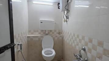 Une salle de bain avec des toilettes, une douche et un seau.