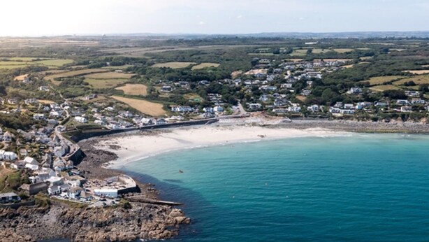 Une ville côtière dotée d’une plage de sable, d’une côte rocheuse et d’immeubles d’habitation.