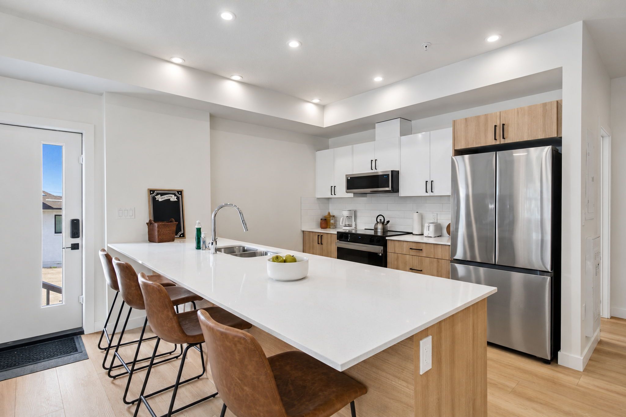 A modern kitchen with a central island, stainless steel appliances, and wooden cabinets.