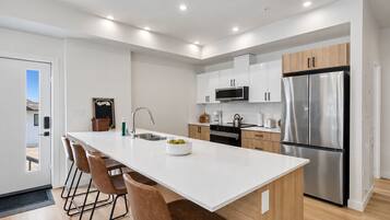 A modern kitchen with a central island, stainless steel appliances, and wooden cabinets.