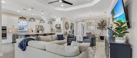 A modern living room with a sectional sofa, a dining area, and a kitchen.