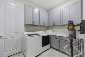 A laundry area with a washing machine, dryer, and a drying rack. - Esplanade by The Islands (Naples)