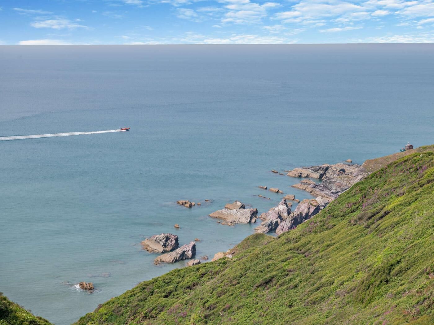 A coastal landscape with rocky outcrops and a clear view of the sea.