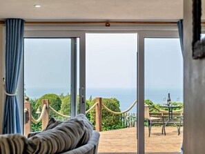 A room with a view of the sea, a wooden deck, and a dining area with a table and chairs. - 1 Bed in Torpoint (oc-37261) (Freathy)