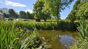 A pond with water lilies and yellow flowers, surrounded by lush greenery and trees. - 1 Bed in Lyme Regis (oc-40483) (Lyme Regis)