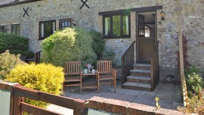 A stone building with a porch, two wooden chairs, a small table, and a staircase leading to an entrance. - 1 Bed in Lyme Regis (oc-40483) (Lyme Regis)