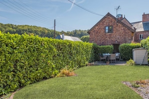 Ein Steinhaus mit einem gepflegten Rasen und einer Hecke.