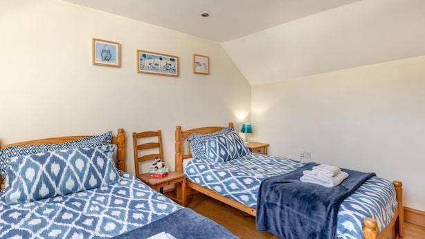 Een slaapkamer met twee eenpersoonsbedden, een nachtkastje met een lamp en wanddecoratie.