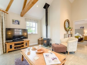 A living room with a TV, fireplace, wooden furniture, and a cozy chair. - 1 Bed in Thirsk (oc-40354) (Sinderby)