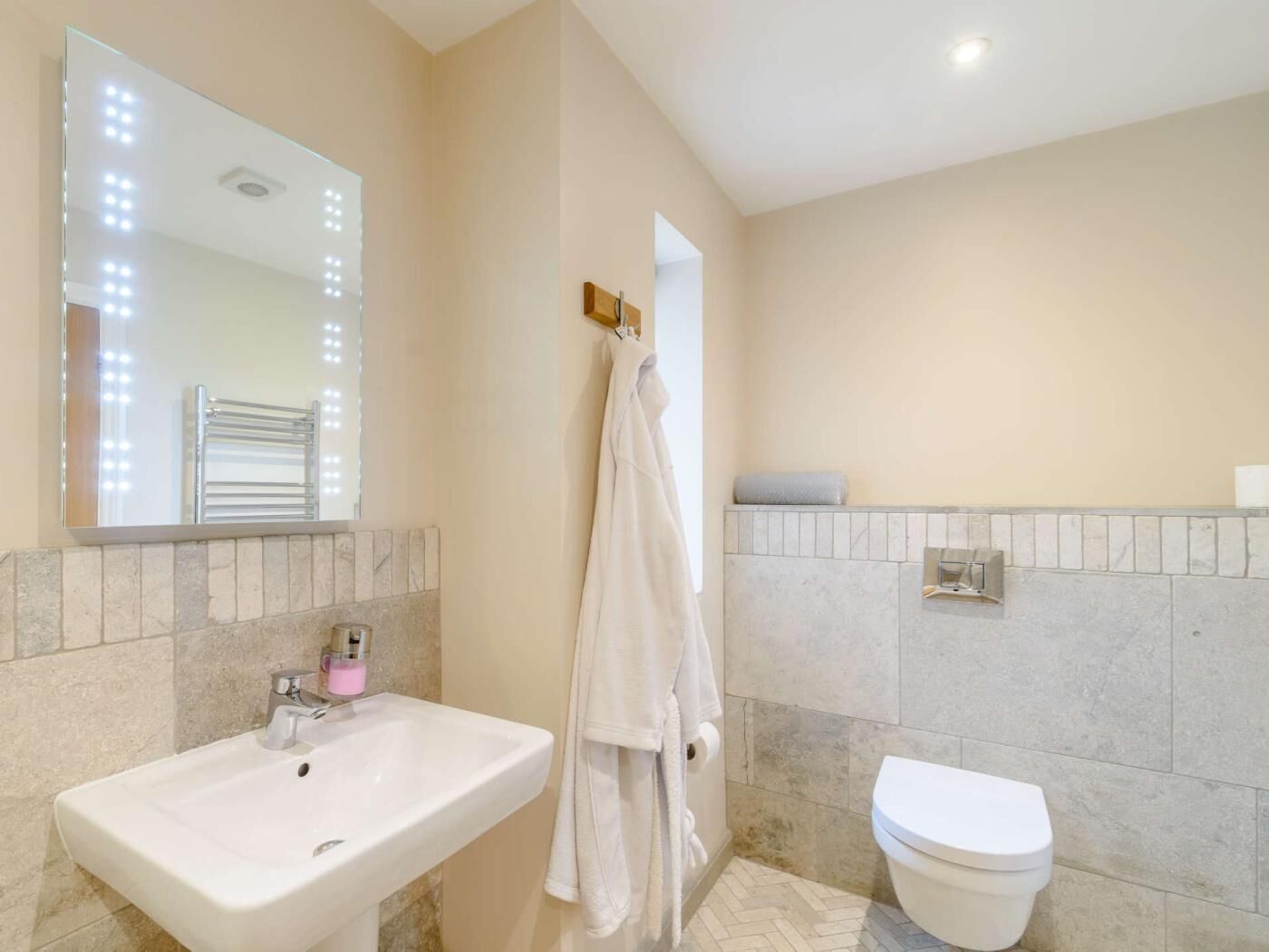 A bathroom with a sink, mirror, towel rack, and toilet.