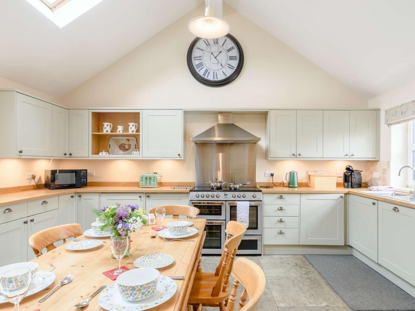 A kitchen with white cabinets, a stove, oven, and a clock on the wall.
