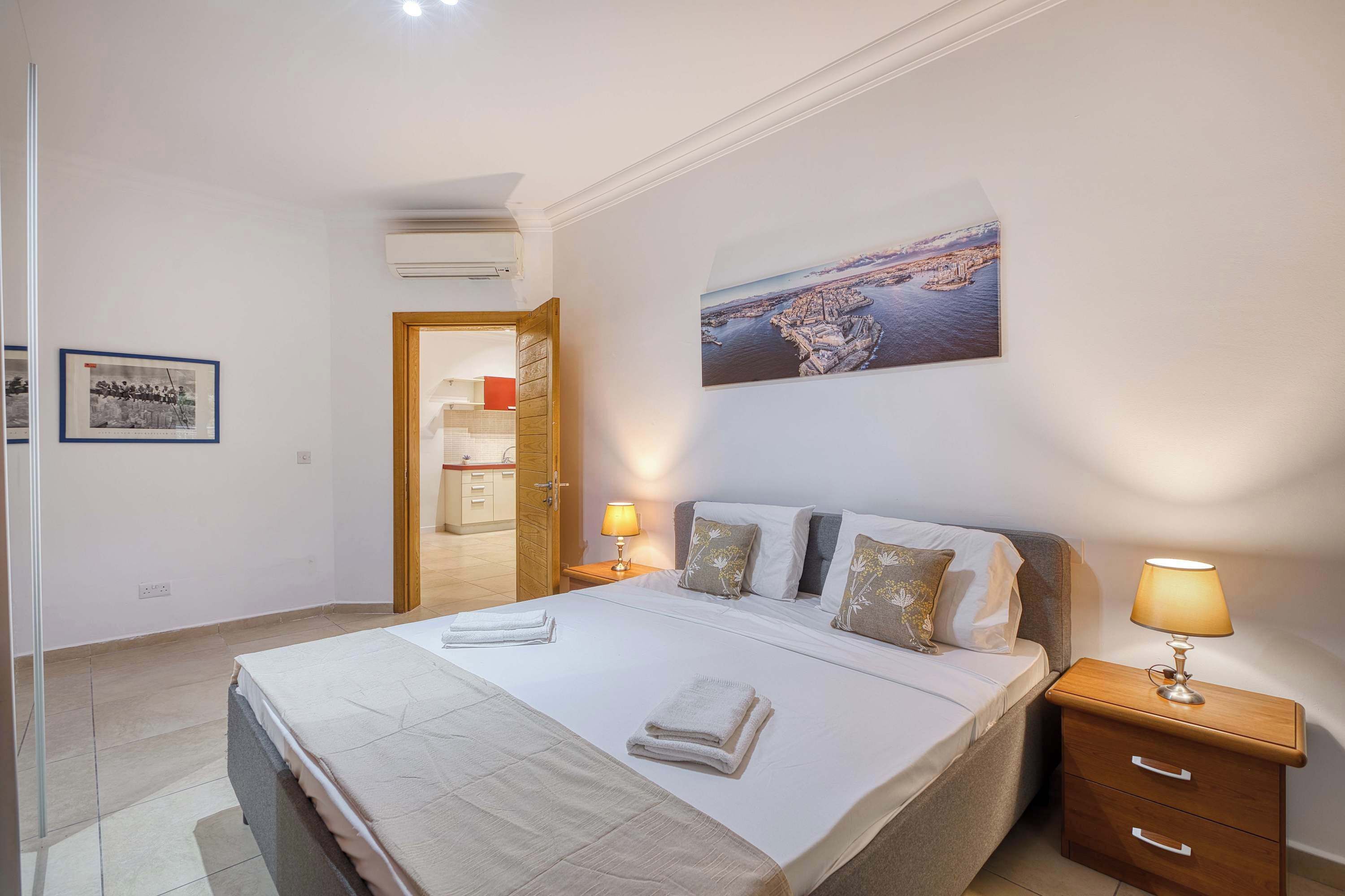 Een hotelkamer met een bed, nachtkastjes, een wanddecoratie en een deur naar een badkamer.