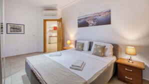 Een hotelkamer met een bed, nachtkastjes, een wanddecoratie en een deur naar een badkamer.