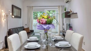 Een eettafel gedekt met borden, glazen en een bloemenboeket als decoratie.