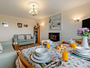 A dining area with a table set for breakfast, including croissants, orange juice, and a pitcher of water.