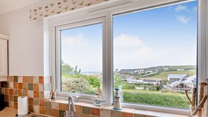 Una cocina con un ventanal amplio, salpicadero de azulejos y vistas al paisaje costero.
