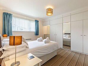 A hotel room with a bed, bedside table, lamp, and a wardrobe.