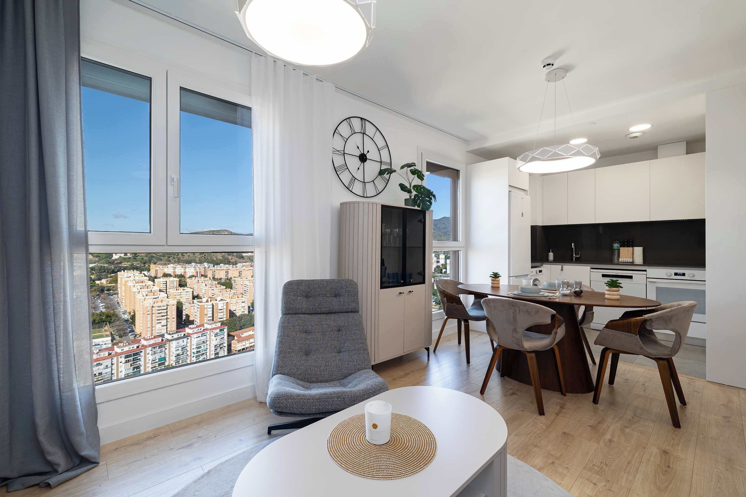 Un apartamento moderno con comedor, cocina y ventanas amplias con vistas a la ciudad.