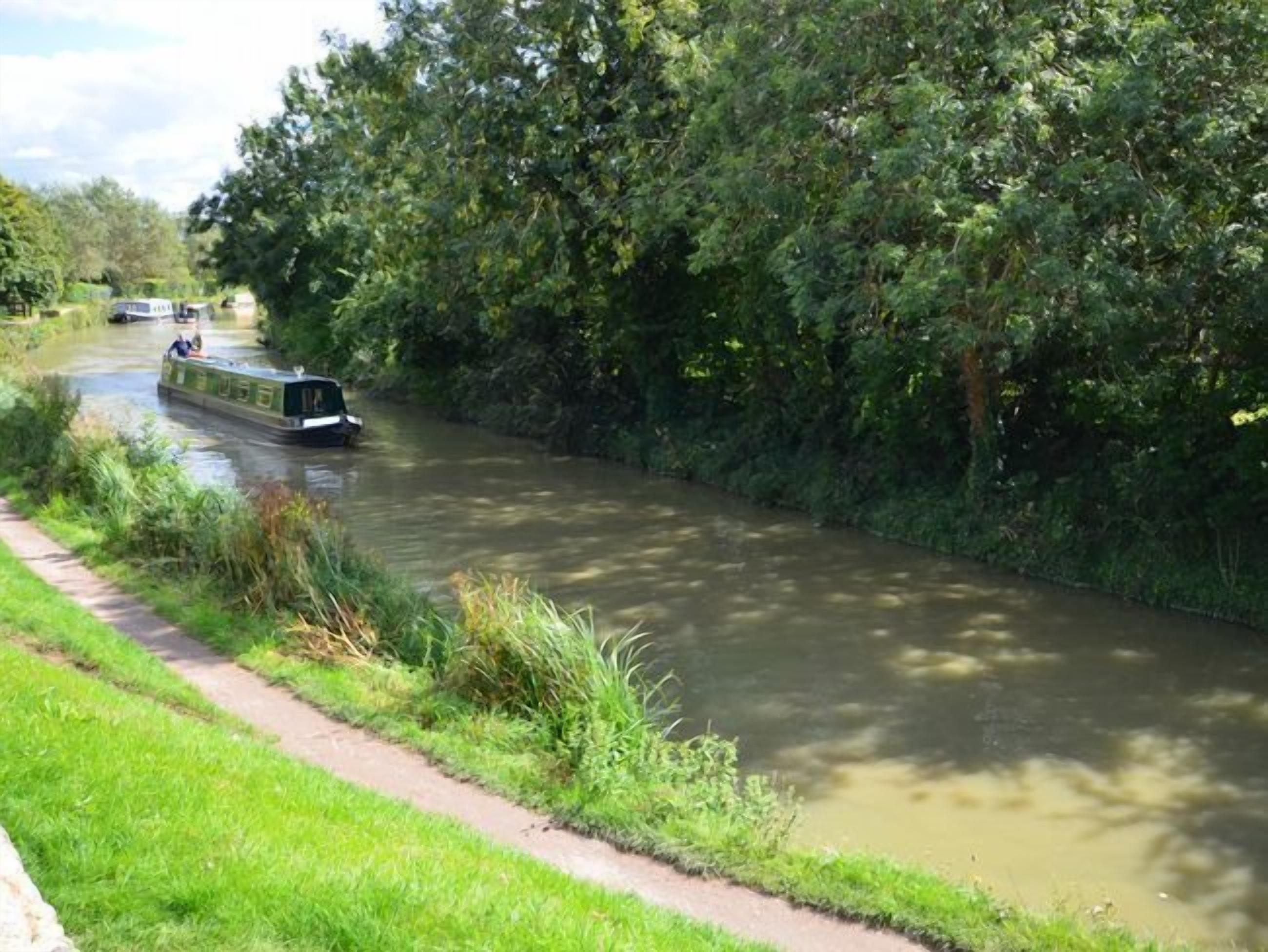 A narrow waterway with boats, surrounded by dense greenery.