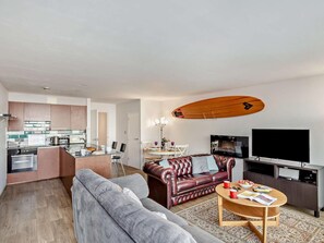 Ein modernes Wohnzimmer mit Sofa, Couchtisch, Fernseher und Küchenbereich mit Esstisch.