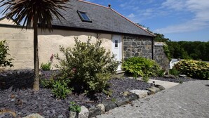 A stone house with a sloped roof, a small window, and a door. - 1 Bed in Helston (oc-41377) (Cury Cross Lanes)