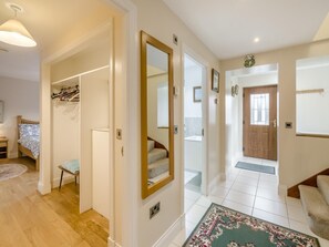 A hallway with a mirror, a coat rack, a bed, and a staircase leading to another room. - 3 Bed in Linlithgow (oc-41422) (Linlithgow)