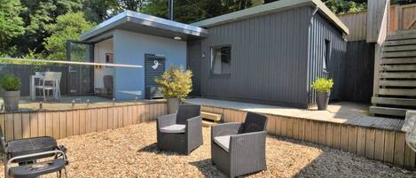 Een terras met buitenmeubilair, een barbecuekar en een gebouw met een blauw dak en een 'Welcome'-bord.