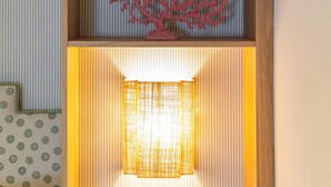 Una habitación con un estante de madera, un adorno de coral rojo y una lámpara encendida.