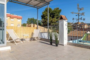 Une terrasse sur le toit, dotée d’un espace salon couvert, de plantes en pot et d’une girouette.