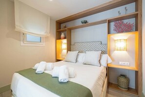 A neatly made bed with rolled towels, a green throw blanket, and a headboard with built-in lighting. - Bright Ground Floor Apt - 700m to Beach (Málaga)
