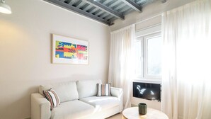 Una sala de estar moderna con un sofá, un cuadro abstracto enmarcado, un televisor y una mesita redonda.