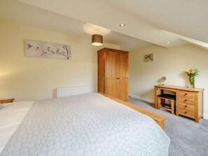 Ein Schlafzimmer mit einem Bett, einem Holzschrank, einem Schreibtisch mit Stuhl und einer Heizung.