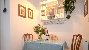 A dining area with a table set for two, a vase with flowers, and a wine bottle. - 2 Bed in Wells (oc-41654) (Wells)