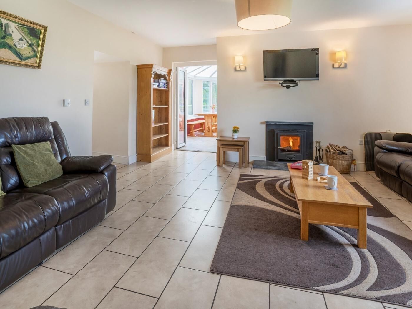 Een moderne woonkamer met een leren bank, een open haard, een flatscreen televisie en een boekenkast.